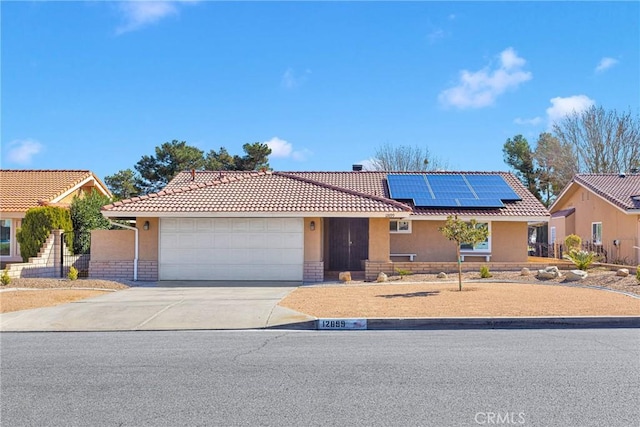12899 Rain Shadow Rd, Victorville, CA 92395 - single story home with an attached garage, roof mounted solar panels, driveway, and stucco siding
