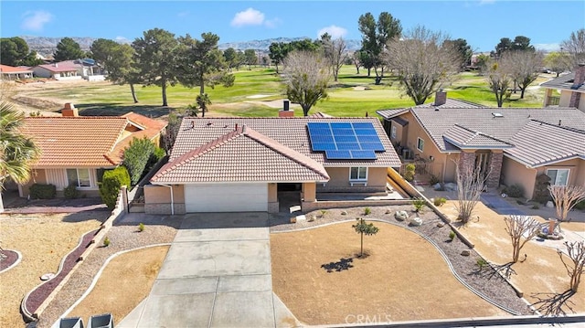 view of front of home with driveway, solar panels, an attached garage, stucco siding, and a tile roof