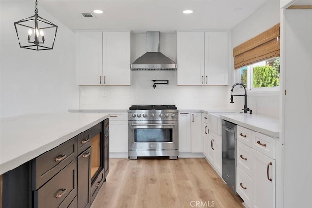 12899 Rain Shadow Rd, Victorville, CA 92395 - kitchen with light wood-type flooring, visible vents, stainless steel stove, wall chimney exhaust hood, and dishwashing machine