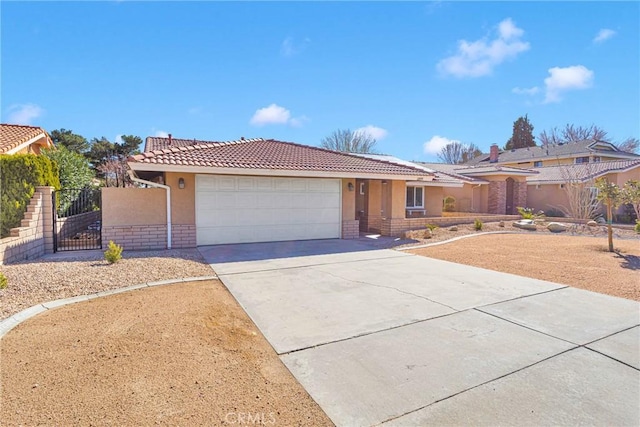 ranch-style home featuring concrete driveway, a tiled roof, a gate, and stucco siding