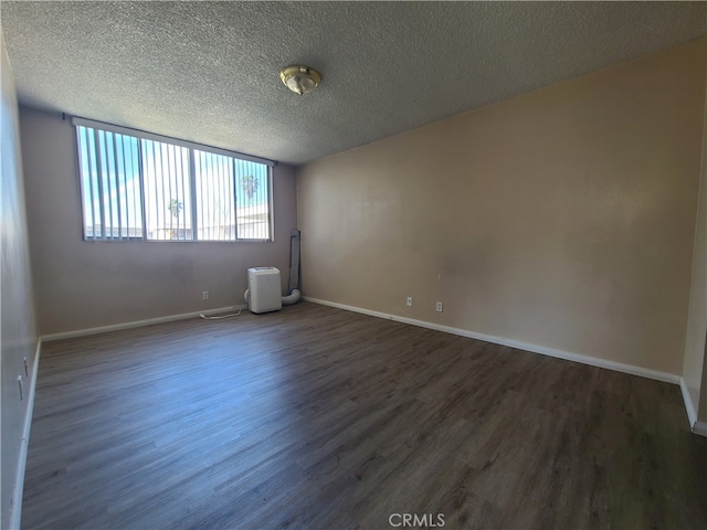 spare room featuring dark wood-style floors, baseboards, and a textured ceiling