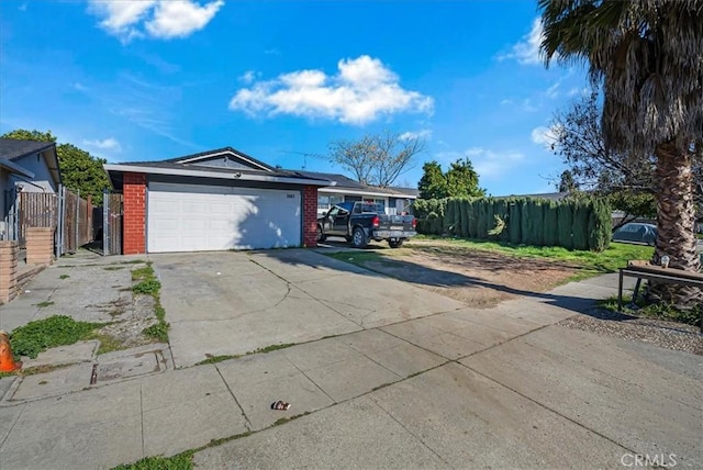 view of front of home with brick siding, an attached garage, concrete driveway, and fence