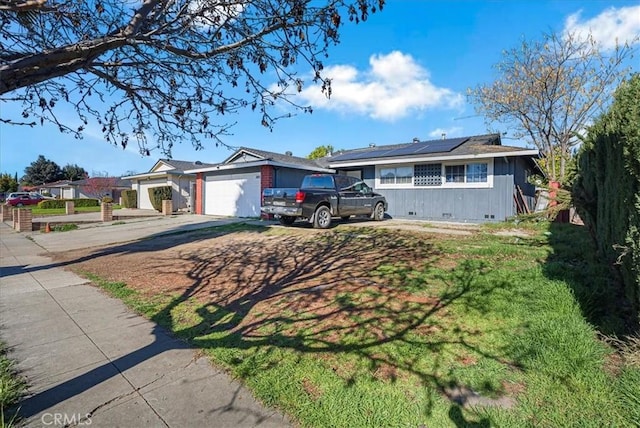 single story home featuring solar panels, concrete driveway, an attached garage, and crawl space