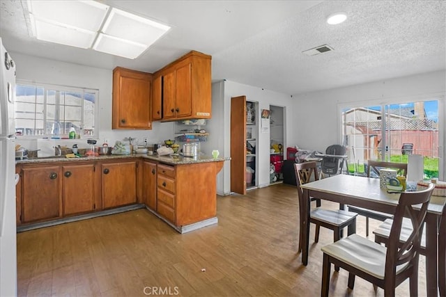 kitchen featuring light wood finished floors, visible vents, brown cabinets, and a wealth of natural light