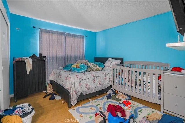 bedroom featuring wood finished floors and a textured ceiling