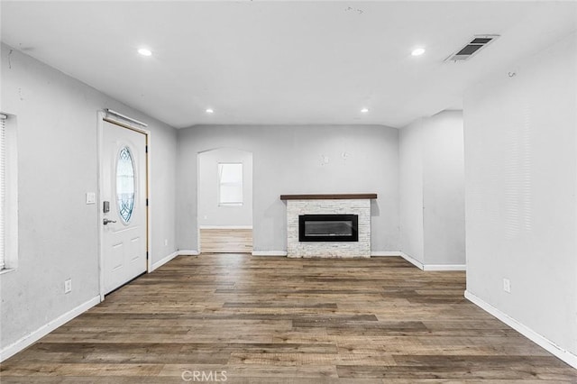 unfurnished living room with wood finished floors, visible vents, baseboards, recessed lighting, and a stone fireplace