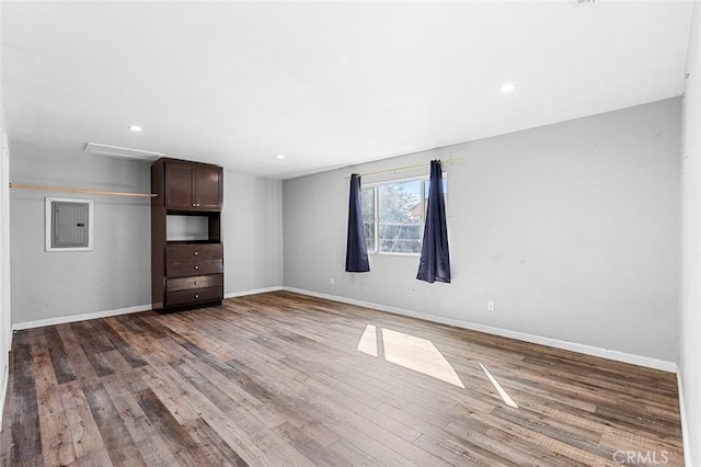 unfurnished living room featuring electric panel, recessed lighting, baseboards, and wood finished floors