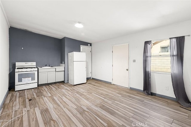 kitchen featuring a sink, white appliances, light countertops, and light wood finished floors