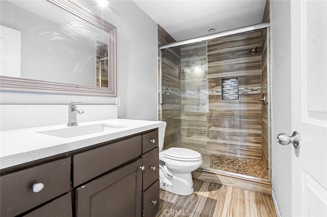 bathroom featuring toilet, a stall shower, and vanity