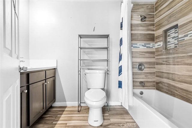 bathroom featuring vanity, wood finished floors, baseboards, shower / bath combo with shower curtain, and toilet