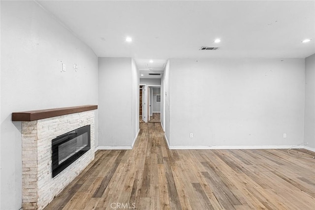 unfurnished living room with visible vents, a fireplace, baseboards, and wood-type flooring