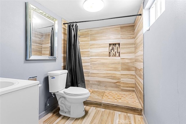 full bathroom featuring tiled shower, toilet, wood finished floors, and vanity