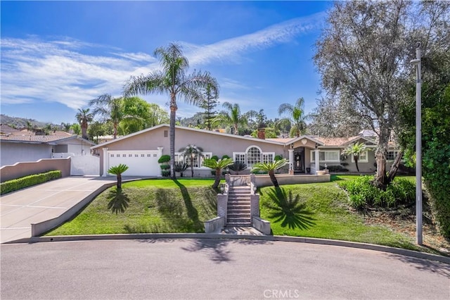 view of front of house featuring stucco siding, a front lawn, an attached garage, and driveway