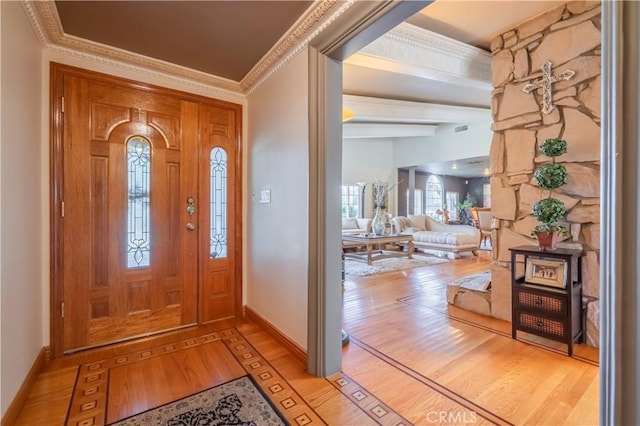 foyer featuring baseboards, visible vents, crown molding, beamed ceiling, and light wood-type flooring