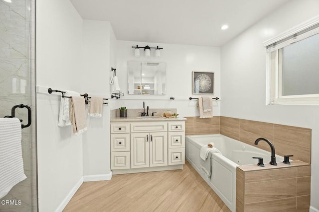 bathroom with vanity, wood finished floors, recessed lighting, a stall shower, and a bath