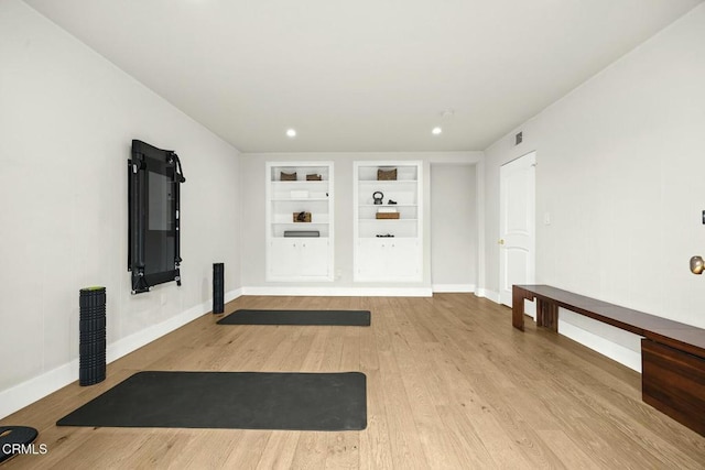 workout room featuring built in features, wood finished floors, and baseboards