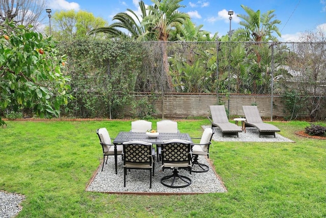 view of yard with a patio area, outdoor dining area, and fence