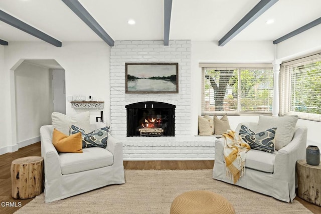 living area with wood finished floors, a fireplace, a wealth of natural light, and beam ceiling