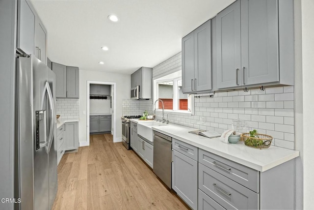 kitchen featuring appliances with stainless steel finishes, gray cabinetry, and a sink