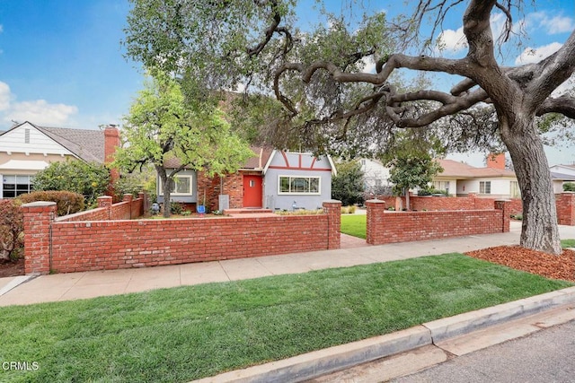 english style home with a front lawn and fence