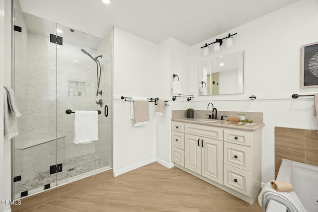 bathroom featuring a shower stall, baseboards, a tub to relax in, wood finished floors, and vanity