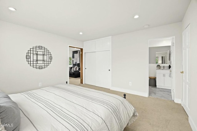 bedroom with baseboards, recessed lighting, a closet, ensuite bathroom, and light colored carpet