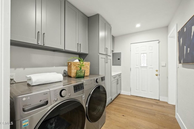 washroom with light wood-type flooring, independent washer and dryer, electric panel, cabinet space, and baseboards