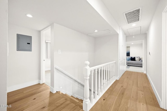 hall with visible vents, attic access, electric panel, an upstairs landing, and hardwood / wood-style flooring