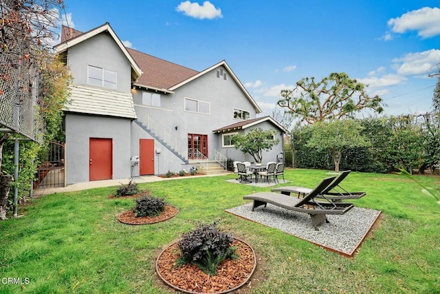 rear view of property with stucco siding, fence, a lawn, and a patio area