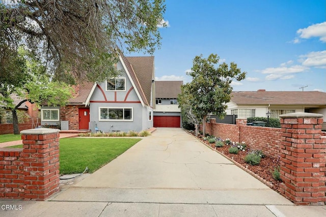 tudor-style house with stucco siding, driveway, fence, a front yard, and a garage