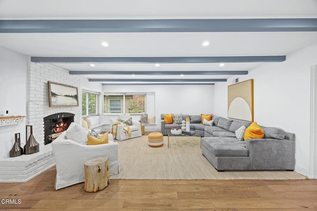 living area featuring recessed lighting, beam ceiling, a brick fireplace, and wood finished floors