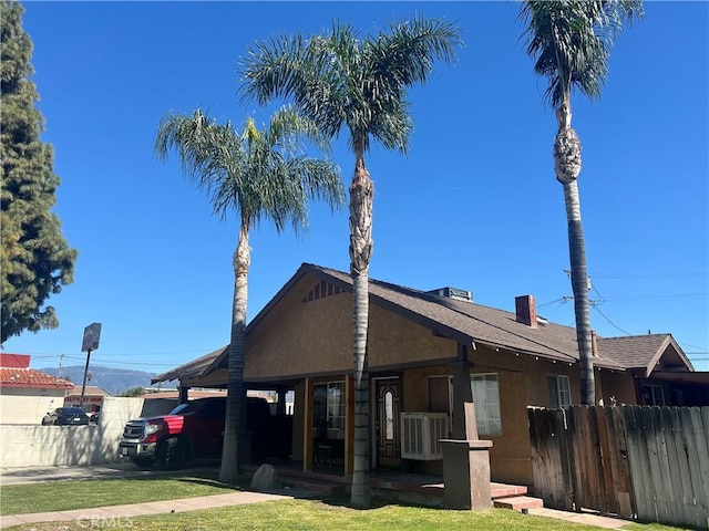 view of front of house with a front yard, fence, a chimney, and stucco siding