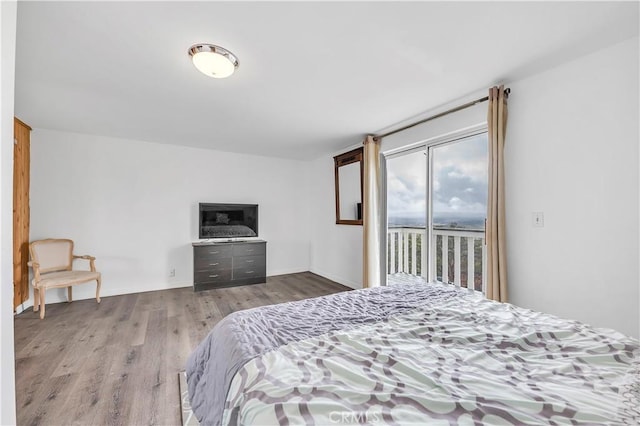 bedroom featuring access to exterior, baseboards, and wood finished floors