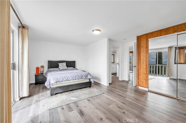 bedroom featuring access to outside, baseboards, and wood finished floors