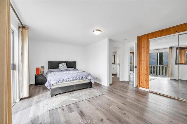 bedroom featuring baseboards, wood finished floors, access to exterior, and multiple windows