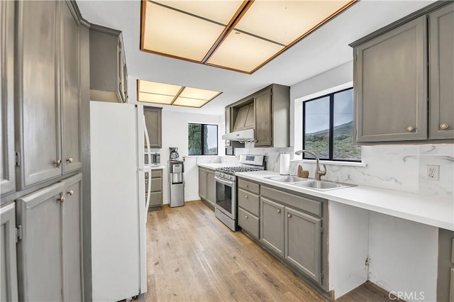 kitchen with a sink, light wood-style floors, appliances with stainless steel finishes, and gray cabinets
