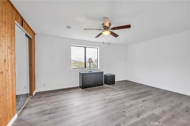 spare room featuring baseboards, wood finished floors, and ceiling fan