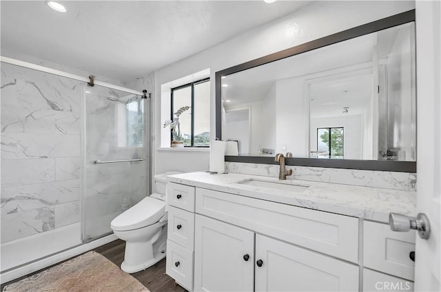 bathroom with toilet, vanity, wood finished floors, and a marble finish shower