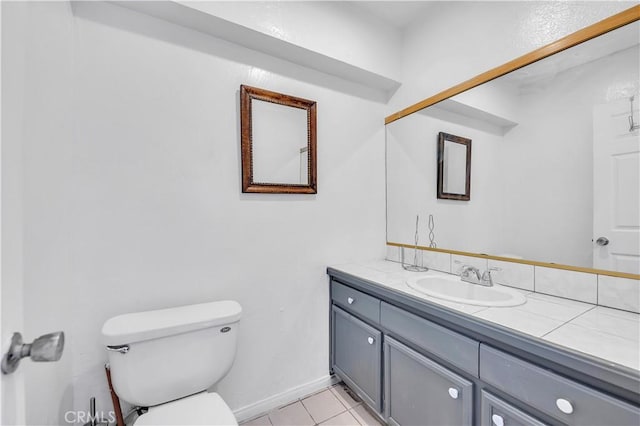 bathroom with tile patterned flooring, toilet, vanity, and baseboards