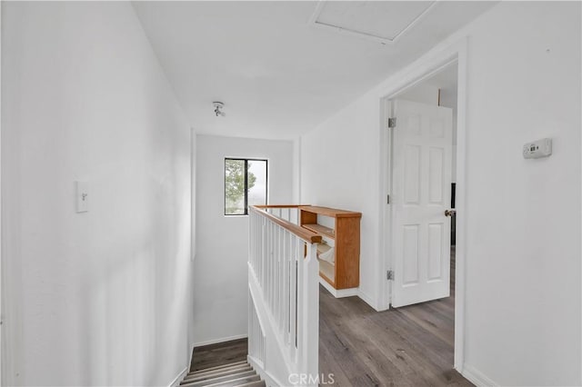 corridor with wood finished floors, an upstairs landing, and baseboards