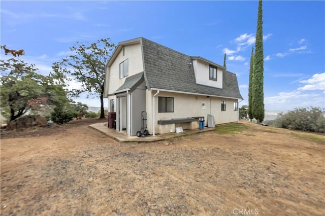 back of house featuring stucco siding and roof with shingles