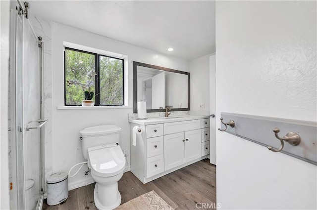 full bathroom with a shower with shower door, wood finished floors, toilet, and vanity