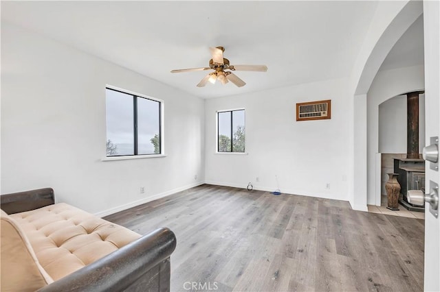 sitting room featuring arched walkways, wood finished floors, baseboards, and ceiling fan