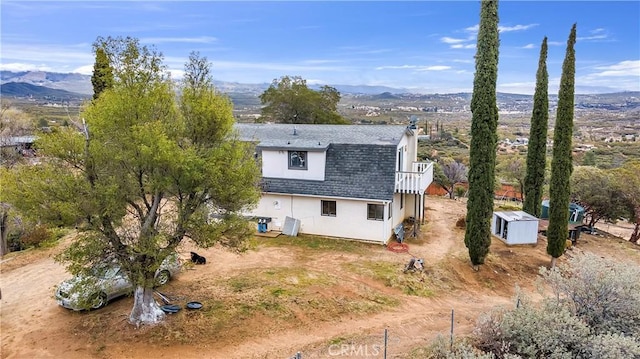 back of property featuring a mountain view, roof with shingles, and a chimney