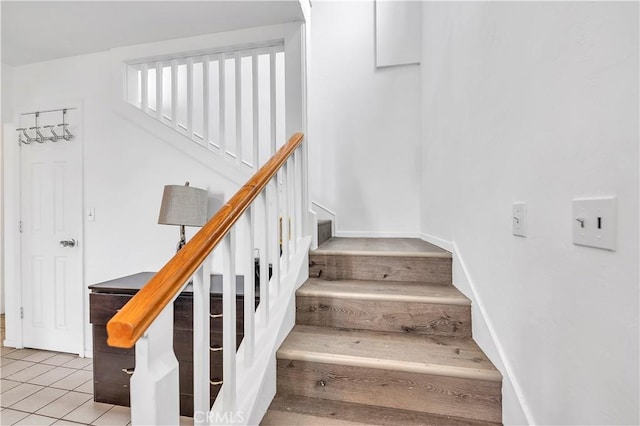 staircase featuring tile patterned floors and baseboards