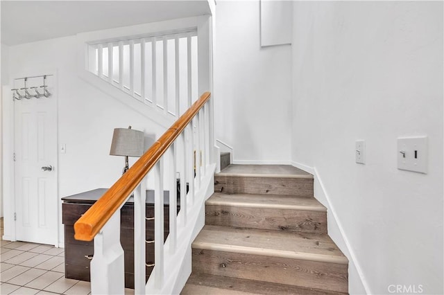 staircase featuring tile patterned floors and baseboards