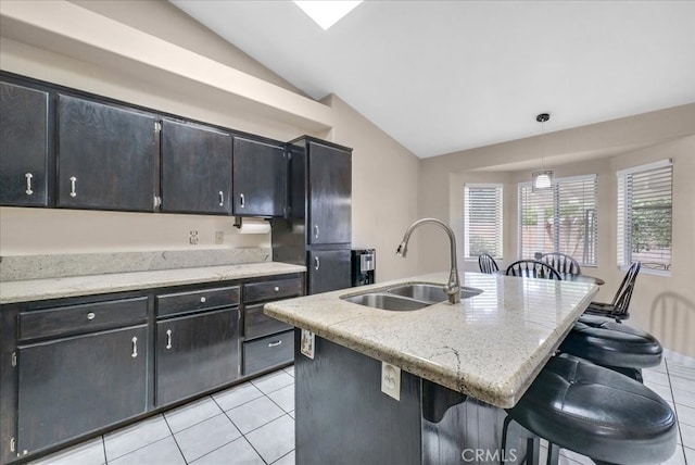 kitchen featuring light tile patterned flooring, a breakfast bar, lofted ceiling, and a sink