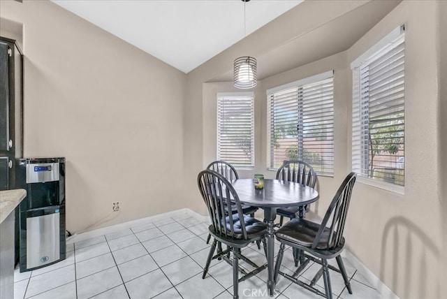 dining area featuring light tile patterned floors, baseboards, and vaulted ceiling