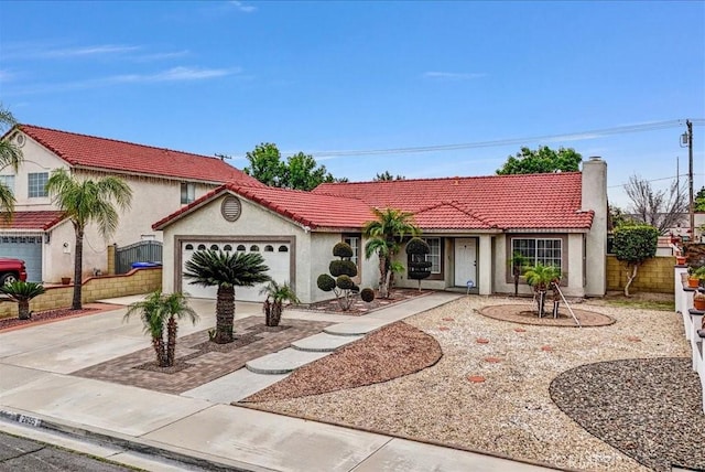 mediterranean / spanish house featuring fence, driveway, a chimney, stucco siding, and a garage