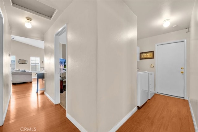 corridor featuring baseboards, washing machine and dryer, attic access, lofted ceiling, and wood finished floors